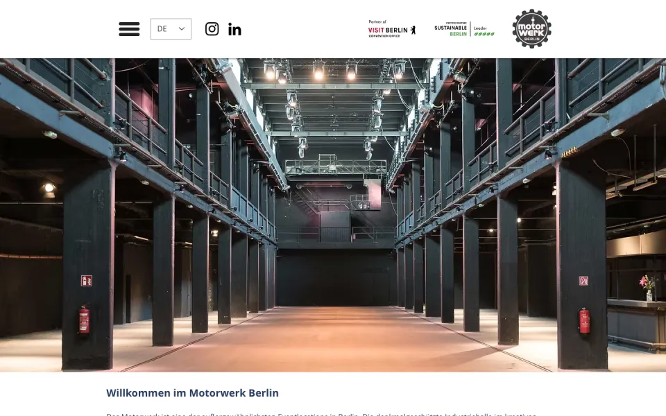Startseite des Motorwerk Berlin am Desktop: Kopfzeile mit Menüknopf, Sprachwahl und Logo, darunter ein großes Foto der leeren Industriehalle mit Stahlträgern und Galerien, Screenshot vom 17.10.2026