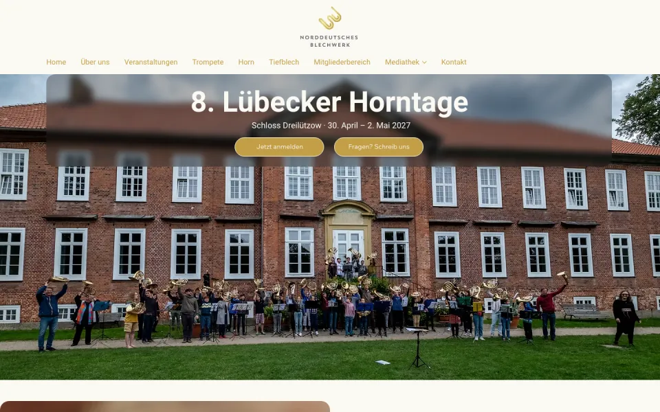 Seite 8. Lübecker Horntage am Desktop: Gruppenfoto von Hornistinnen und Hornisten vor dem Backsteinbau von Schloss Dreilützow, darüber Titel, Ort und Datum und zwei goldene Knöpfe, Screenshot vom 17.10.2026