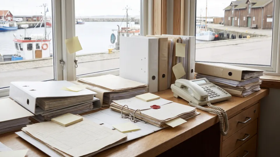 Tresen in einem Büro am Hafen mit Aktenordnern, Formularstapeln, Haftnotizen und Telefon
