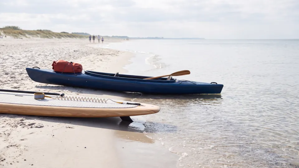 SUP-Board und Kajak am Ufer im ruhigen Flachwasser