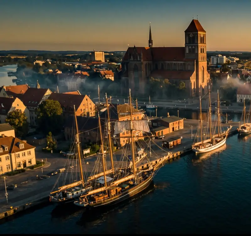 Rostocker Stadthafen mit Traditionsseglern und der Marienkirche im Abendlicht