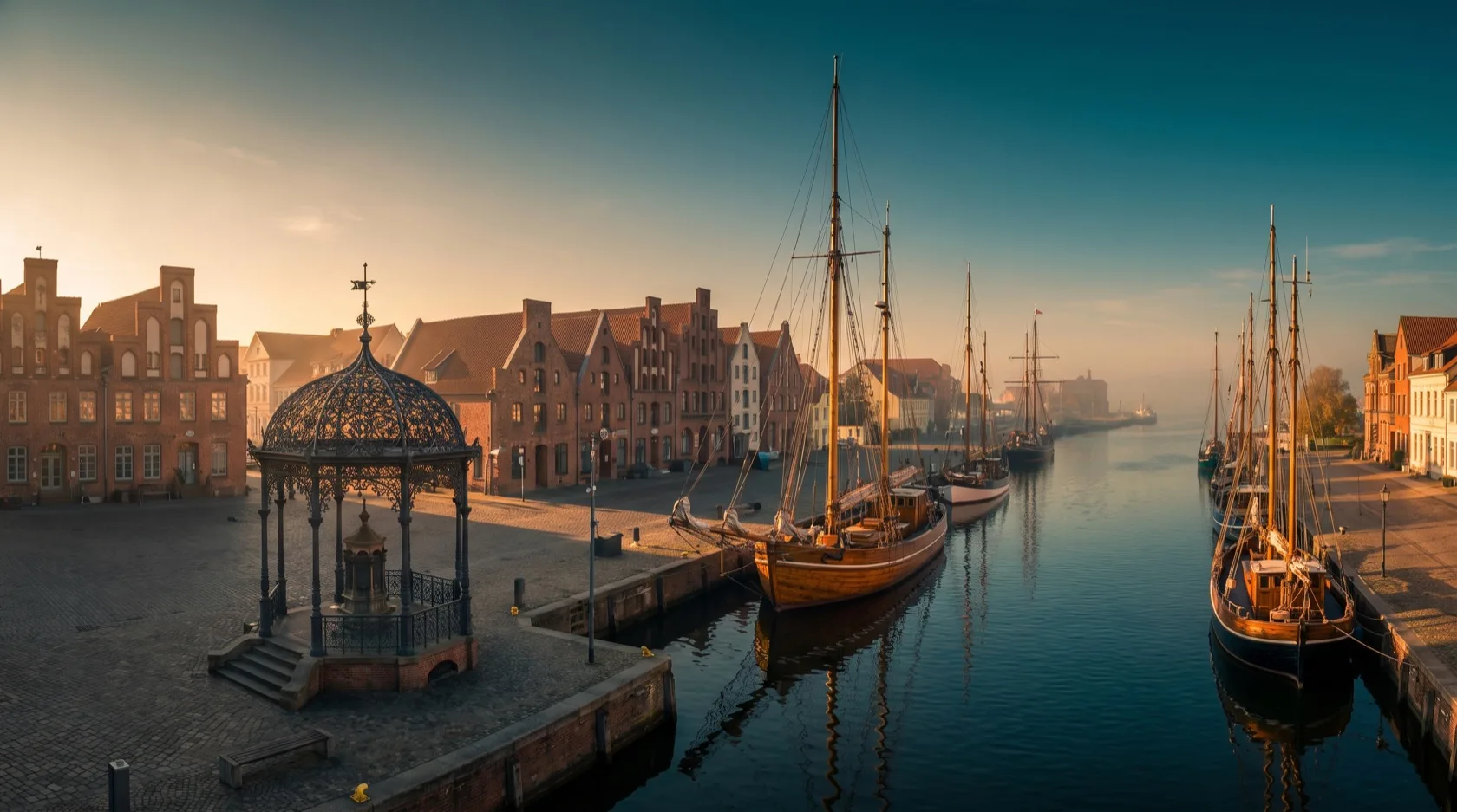 Wismar am Wasser: der Alte Hafen mit der Wasserkunst am Markt, historische Backsteingiebel und die UNESCO-Altstadt im Abendlicht